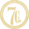 Gold circular 7Cs Cafe emblem with a large 7Cs monogram in the center, ringed by the words Coffee, Chocolate and Cookies above and Cut, Color, Clarity and Carat below